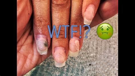 why are my nails green under my fake nail